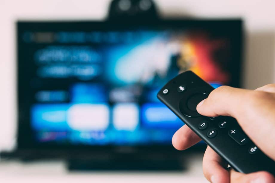 A person holding a remote control in front of a tv.