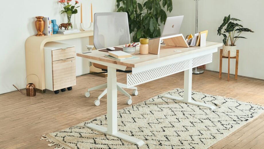A white desk with a laptop on it and a plant on it.