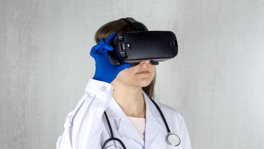 Person in a white lab coat and blue gloves wearing a virtual reality headset, with a stethoscope around their neck.